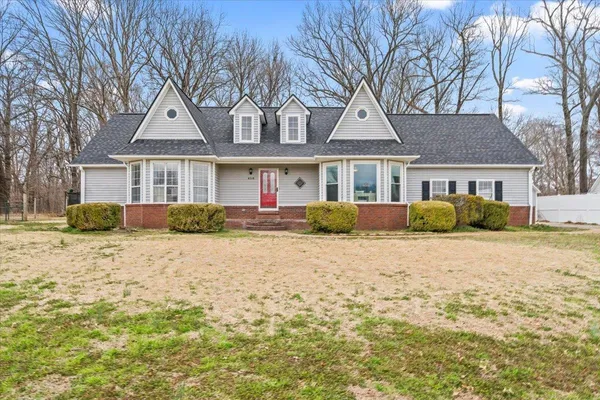 a front view of a house with a dirt yard and a large tree
