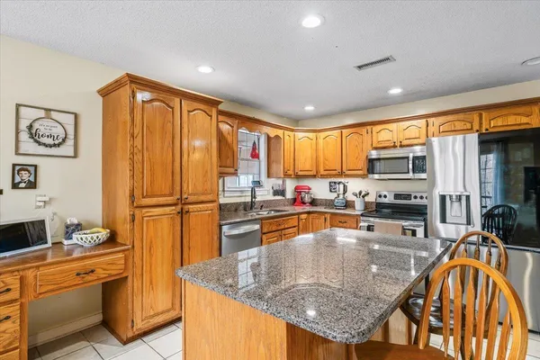 a kitchen with stainless steel appliances granite countertop a refrigerator a stove top oven a sink and dishwasher