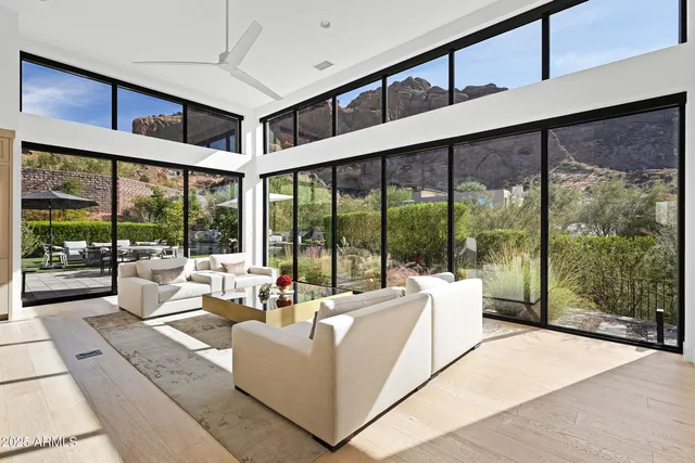 a living room with furniture large windows and view of big yard