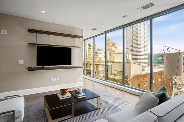 a living room with furniture a flat screen tv and a floor to ceiling window