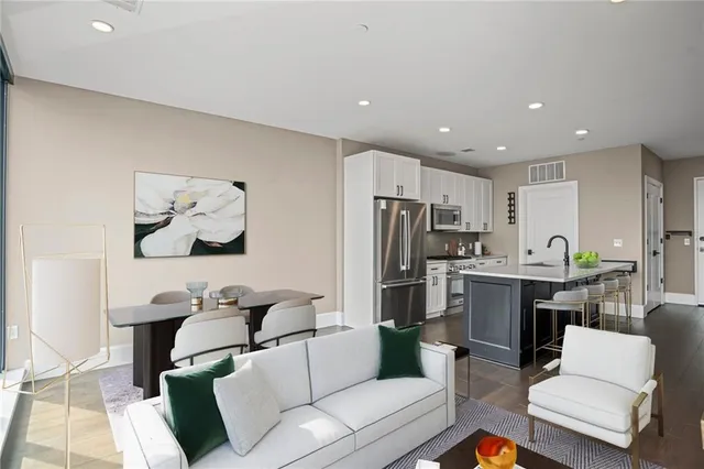 a living room with stainless steel appliances furniture and a kitchen view