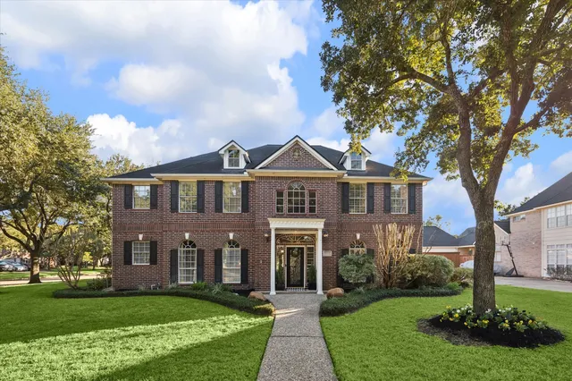 a front view of a house with a garden and trees