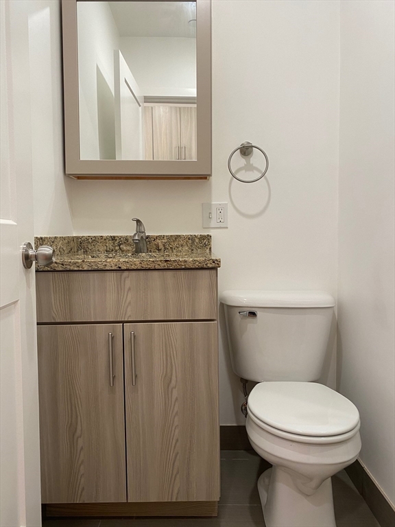 16 5th Street, Unit 6 Chelsea, MA 02150 - Photo 4 of 7 a bathroom with a granite countertop toilet a sink and a mirror
