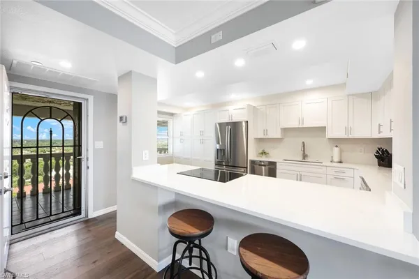 a kitchen with kitchen island a stove a refrigerator and a dining table with wooden floor