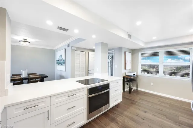 a large white kitchen with stainless steel appliances kitchen island granite countertop a sink and cabinets