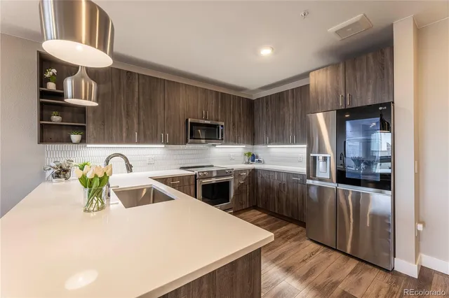 a kitchen with stainless steel appliances a sink a stove a refrigerator cabinets and a counter top space