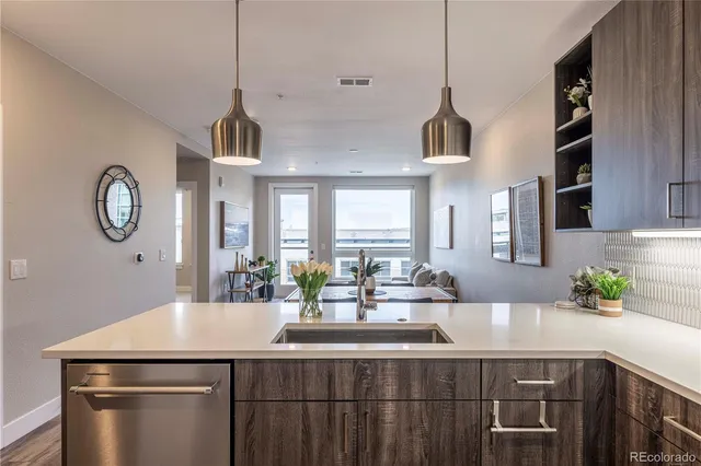 a kitchen with a sink a chandelier stainless steel appliances and cabinets