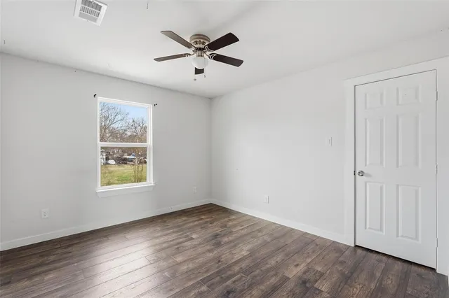 a view of empty room with wooden floor and ceiling fan