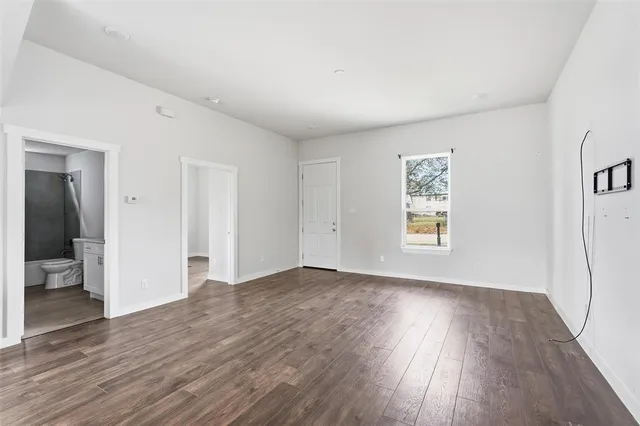 an empty room with wooden floor & windows and bathroom