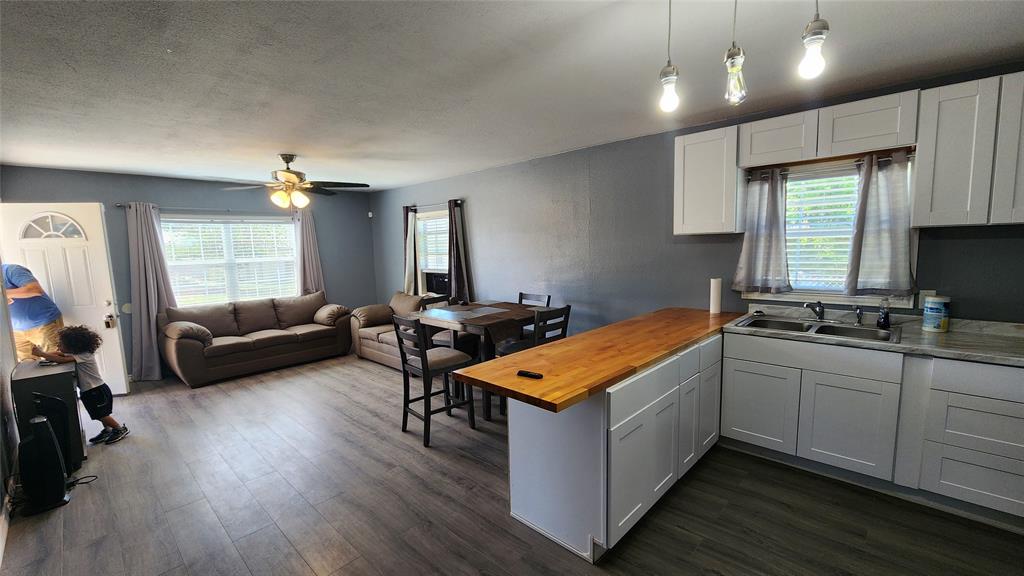 809 Bowie Street Sweetwater, TX 79556 - Photo 19 of 20 Kitchen featuring a sink, wooden counters, a peninsula, open floor plan, and dark wood-style flooring