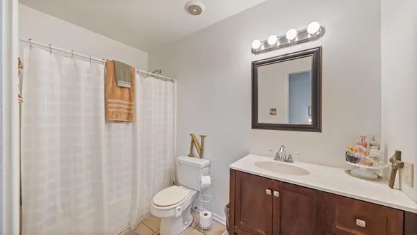 a bathroom with a toilet a sink a mirror a vanity and shower