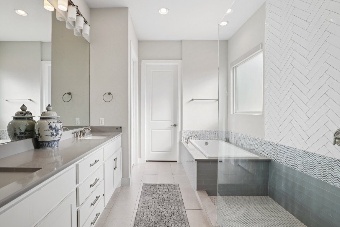 101 Cascading Water Place Austin, TX 78734 - Photo 18 of 36 a spacious bathroom with a double vanity sink a mirror and a bathtub