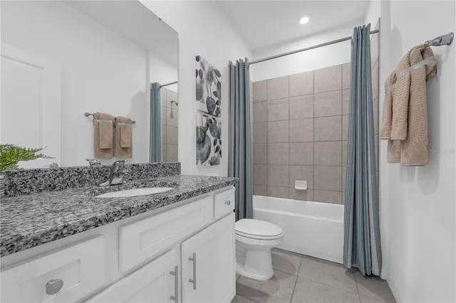 a bathroom with a granite countertop bathtub shower sink vanity and toilet