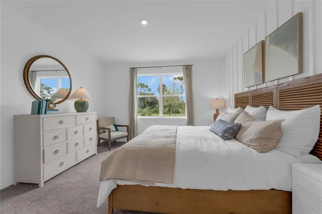 a bedroom with a bed a mirror on dresser and a window