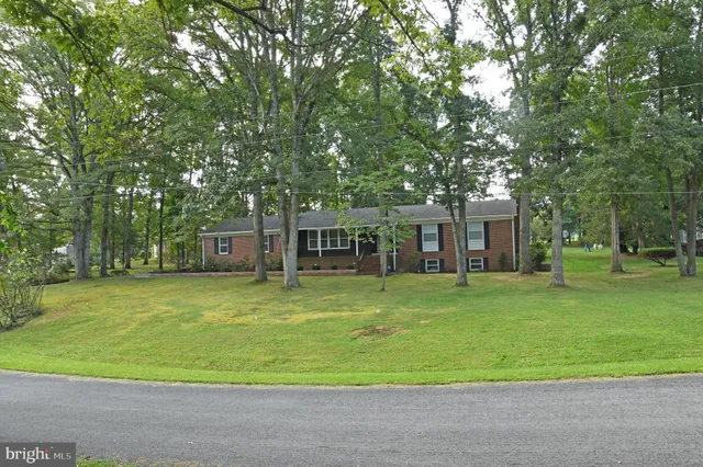 a front view of a house with a big yard and trees