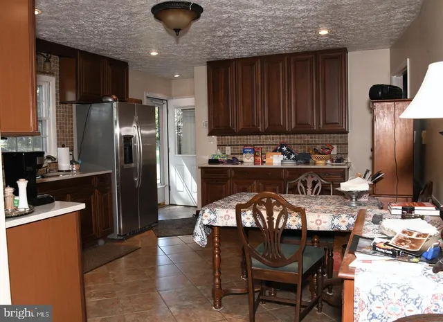 a kitchen with stainless steel appliances granite countertop a table chairs sink refrigerator and microwave