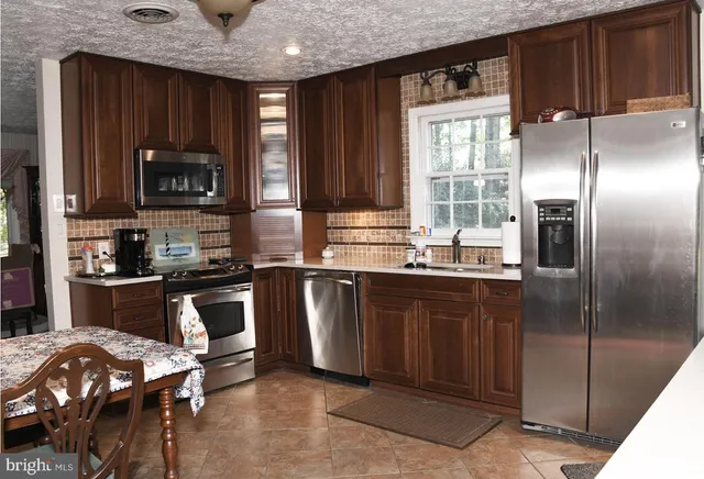 a kitchen with granite countertop a refrigerator stove top oven a sink and dishwasher