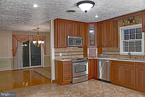 a view of a kitchen with stainless steel appliances granite countertop a sink and cabinets