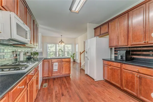 a kitchen with stainless steel appliances granite countertop a refrigerator a stove top oven and sink with wooden floors