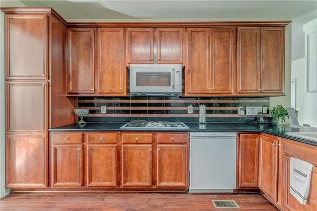 a kitchen with granite countertop wooden cabinets a sink and a stainless steel appliances