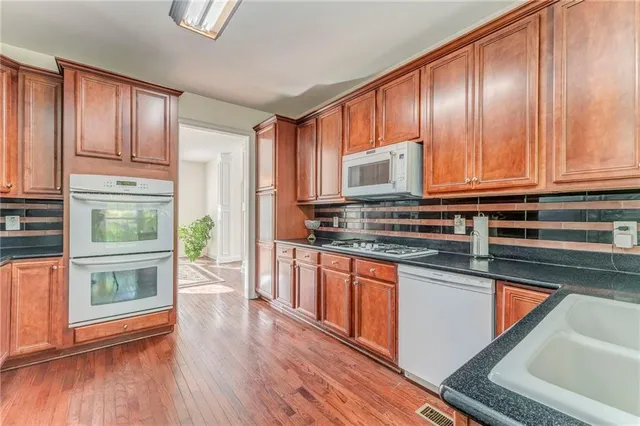 a kitchen with stainless steel appliances granite countertop wooden cabinets a stove a sink and dishwasher with wooden floor