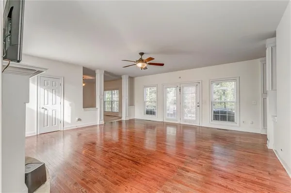 a view of an empty room with wooden floor and a window