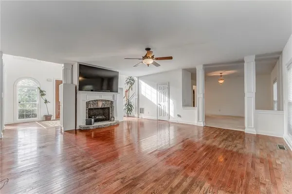 an empty room with wooden floor a fireplace and windows