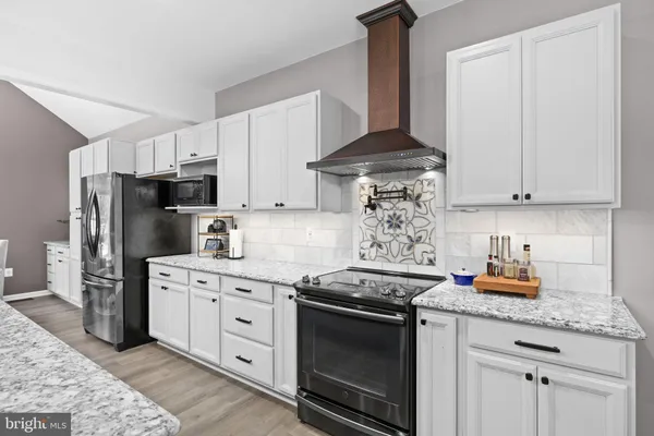 a kitchen with granite countertop a stove a sink a kitchen island with chairs and wooden floor