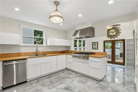 a kitchen with stainless steel appliances kitchen island granite countertop a table chairs in it and wooden floors