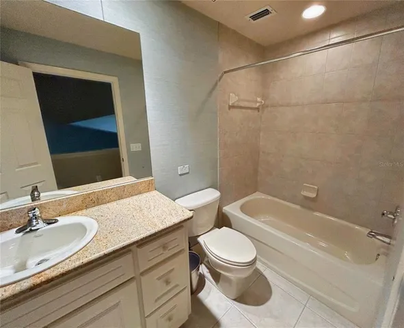 a bathroom with a granite countertop sink a toilet a mirror and bathtub