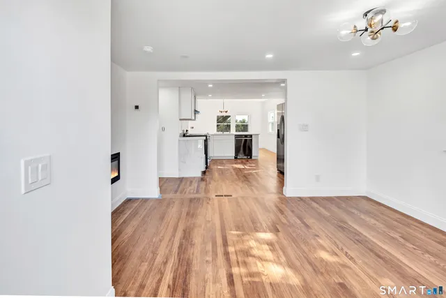 a view of a living room with kitchen island stainless steel appliances wooden floor and view living room