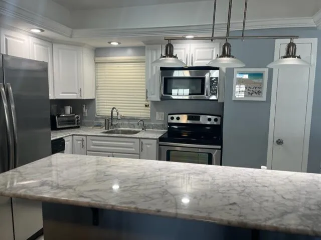 a kitchen with stainless steel appliances granite countertop a sink refrigerator and microwave