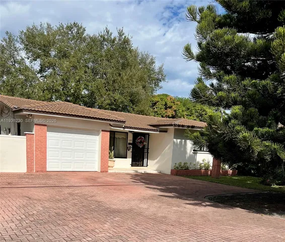 a view of a white house with a tree and plants