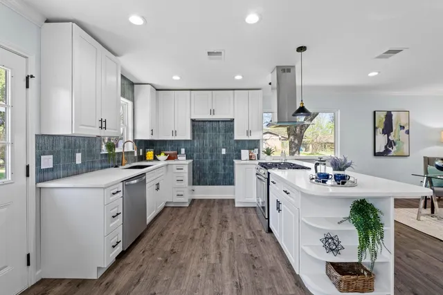 a large kitchen with stainless steel appliances lots of counter space white cabinets and wooden floor