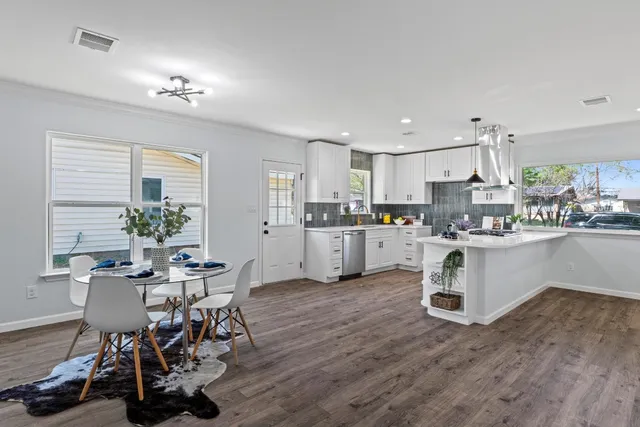 a kitchen with a table chairs a sink dishwasher and cabinets