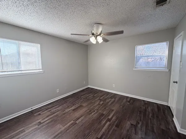 a view of a room with wooden floor and a ceiling fan