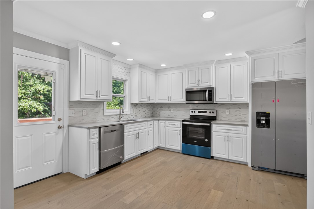 712 Beech Drive Seneca, SC 29678 - Photo 13 of 41 White cabinetry and stainless appliances create a crisp, functional culinary space with warm wood flooring.