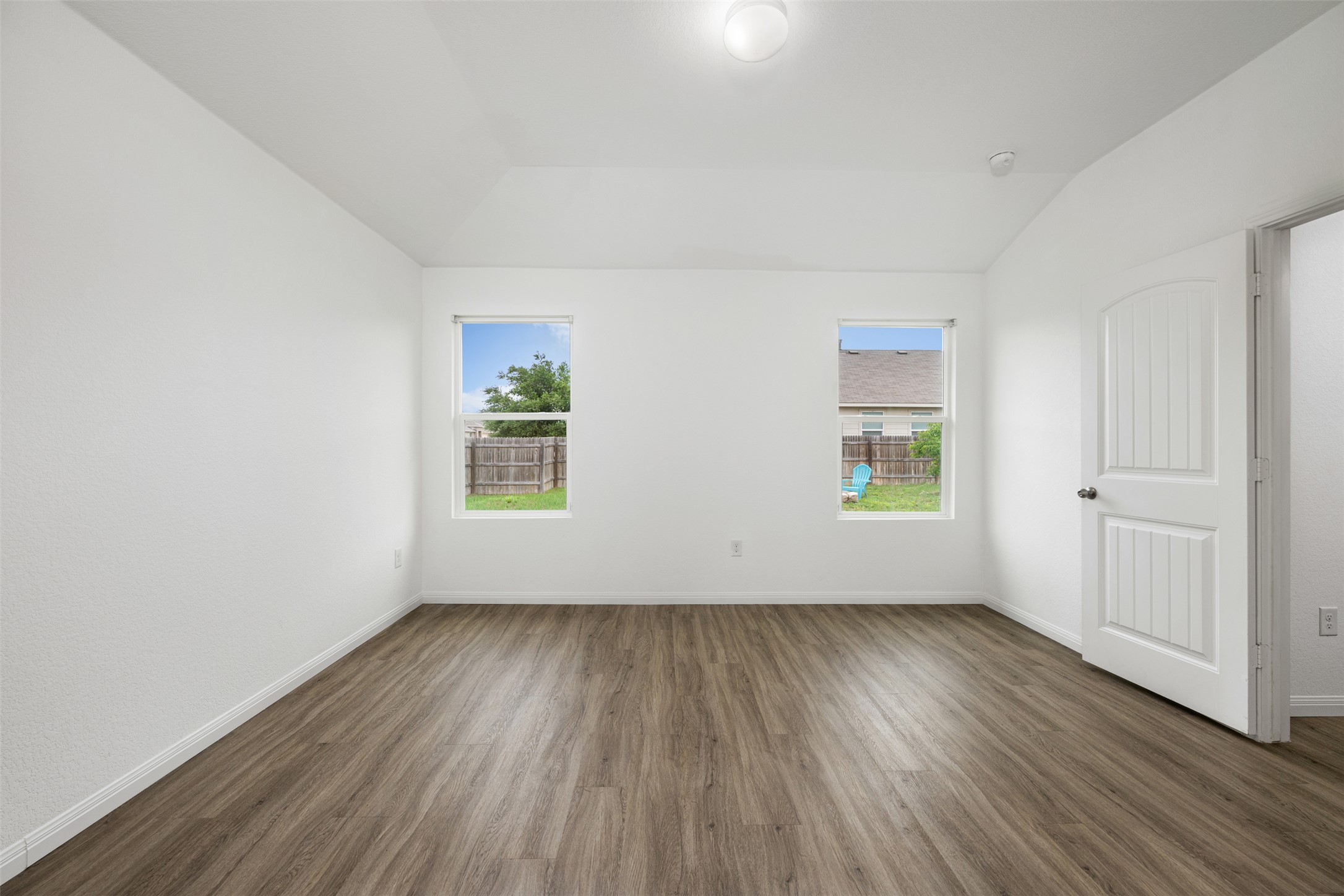 14900 Retha Pass Austin, TX 78725 - Photo 16 of 39 Spacious room featuring wood-finish flooring, crisp white walls, two windows, and a white paneled door