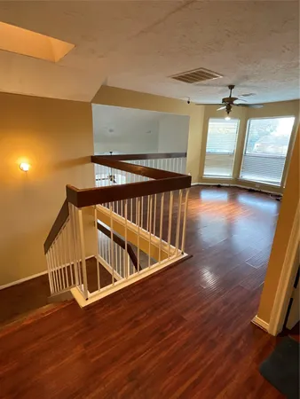 a view of an empty room with wooden floor and windows