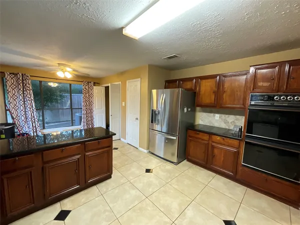 a kitchen with granite countertop a refrigerator and a stove top oven