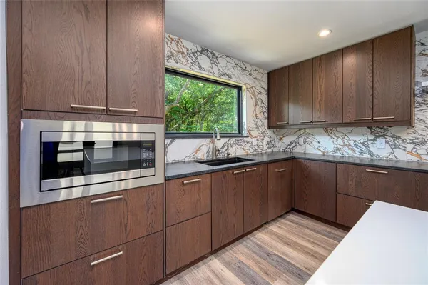 a view of kitchen with granite countertop white cabinets and stainless steel appliances