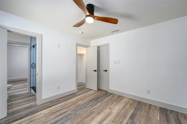 an empty room with wooden floor ceiling fan and windows