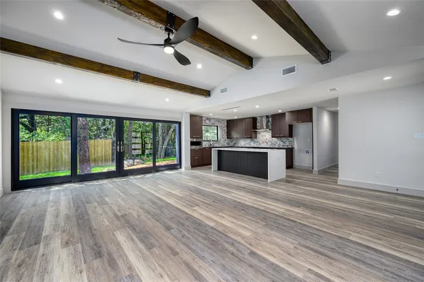 a view of an empty room with window and wooden floor