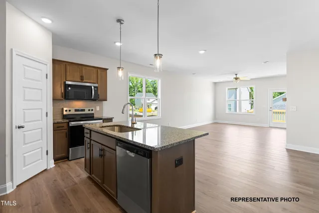 a kitchen with granite countertop a stove top oven a sink dishwasher a dining table and chairs with wooden floor