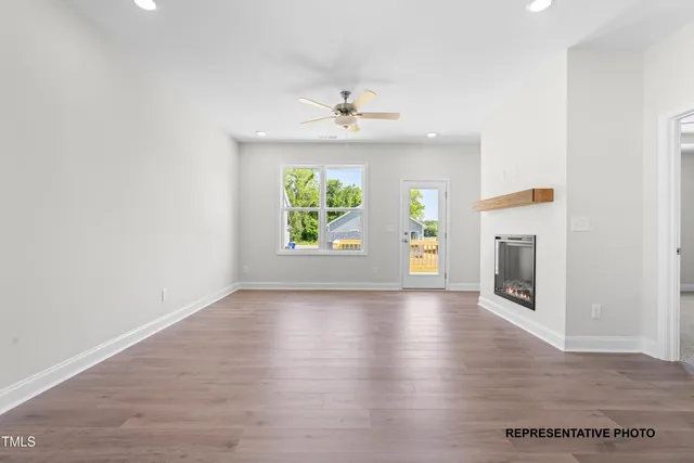 an empty room with wooden floor a ceiling fan and a window