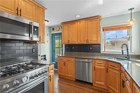 a kitchen with stainless steel appliances granite countertop a stove a sink and a microwave