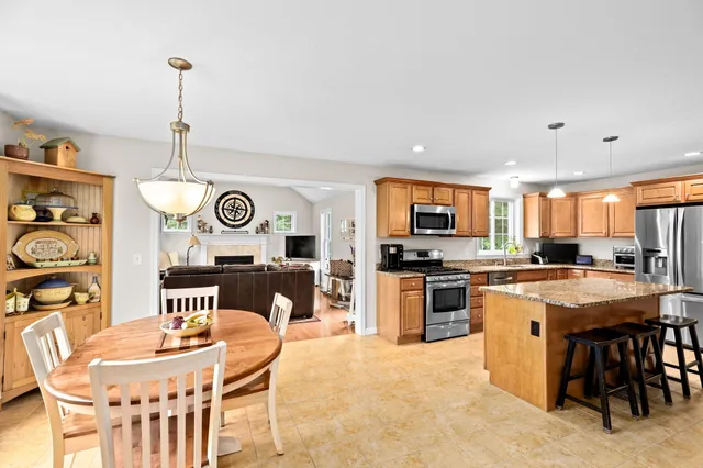 a kitchen with stainless steel appliances granite countertop a kitchen island a stove a table and chairs