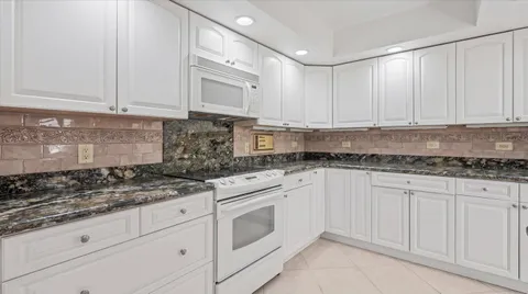 a kitchen with granite countertop white cabinets and white appliances