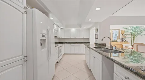 a large white kitchen with a sink and refrigerator