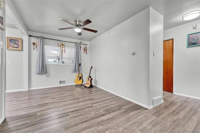 a view of empty room with wooden floor and fan
